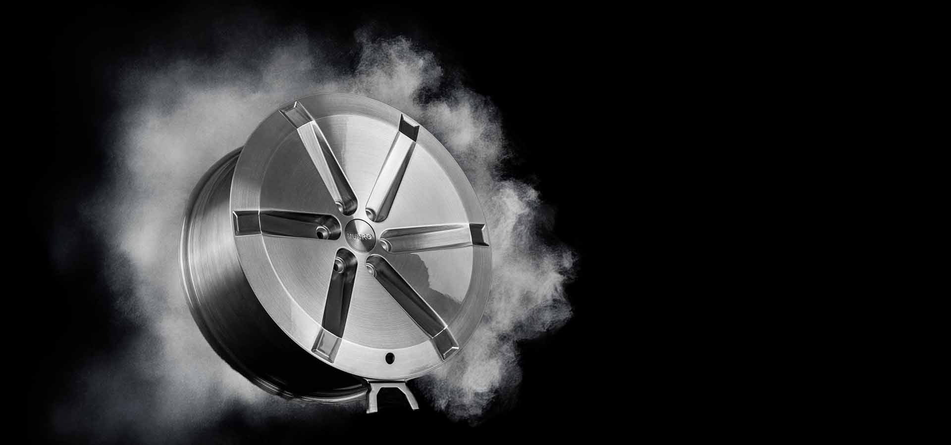 Munro Delta Wheel CYBRWHL brushed aluminum style with smoke around it like a burnout.